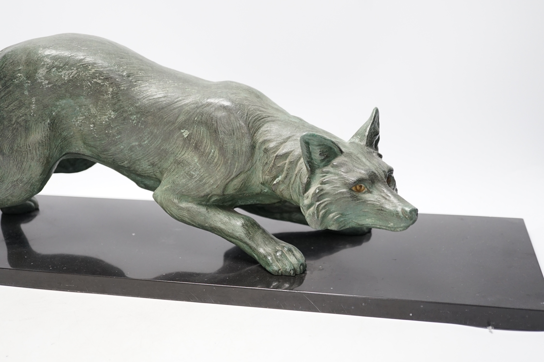 A bronzed metal model of a stalking fox, on black marble plinth, 62cm